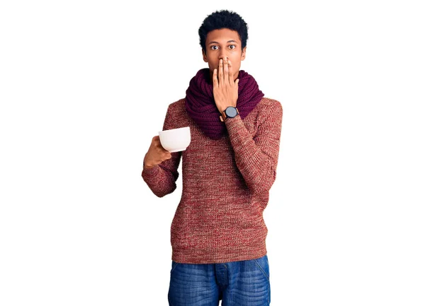 冬のスカーフを着用し 手で口をカバー熱いコーヒーを飲んでいる若いアフリカ系アメリカ人男性は ショックを受け 間違いを恐れています 驚きの表情 — ストック写真