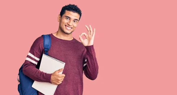 Joven Joven Guapo Hispano Usando Mochila Estudiante Cuaderno Haciendo Signo —  Fotos de Stock