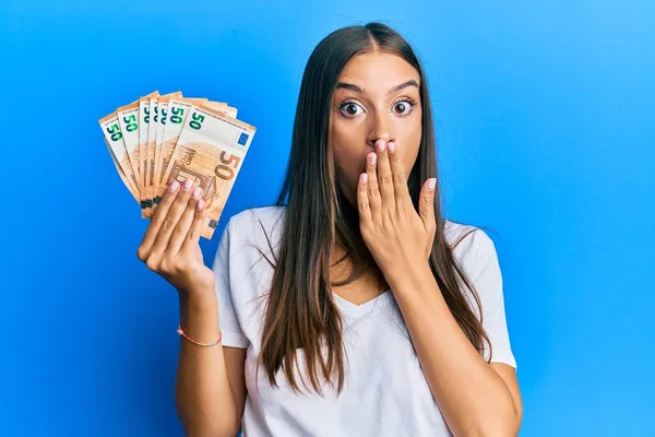 Young Hispanic Woman Holding Euro Banknotes Covering Mouth Hand Shocked — Stock fotografie