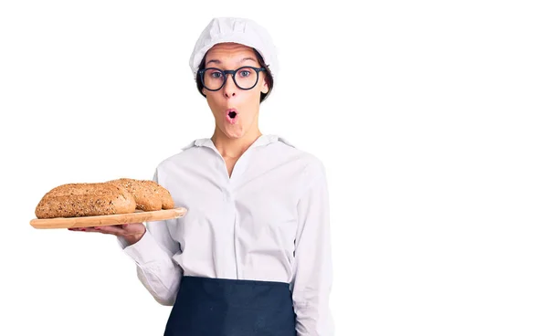 Schöne Brünette Junge Frau Bäckeruniform Hält Hausgemachtes Brot Erschrocken Und — Stockfoto