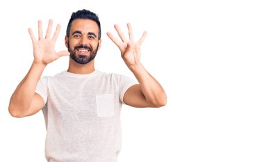 Gündelik kıyafetler giyen genç İspanyol adam dokuz numarayı gösterip işaret ederken kendinden emin ve mutlu bir şekilde gülümsüyor.. 