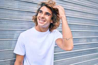 Genç, yakışıklı, gülümseyen bir İspanyol. Şehrin caddesinde mutlu bir şekilde yürüyor.