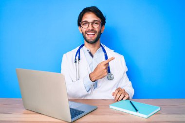 Yakışıklı, doktor üniforması giyen, klinikte çalışan, gülümseyen, el ve parmak uçlarında gezen bir İspanyol. 