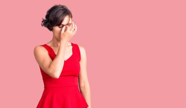 Kısa saçlı, sıradan giyinen, kolsuz tişörtlü, burnu ve gözleri ovuşturmaktan yorgun düşmüş yorgun ve başı ağrıyan güzel bir kadın. Stres ve hüsran kavramı. 