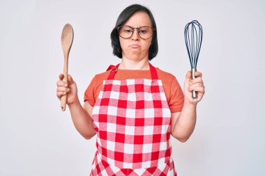 Esmer kadın, aşçı fırça ve kaşık kullanarak yemek pişiriyor. Yüzünde ciddi bir ifadeyle rahatlıyor. Basit ve doğal bir şekilde kameraya bakıyorsun.. 