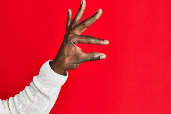 アフリカ系アメリカ人の黒人青年の腕と手で 赤い隔離された背景のピッキングと目に見えないものを取り 指で空間を示すオブジェクトを保持する — ストック写真