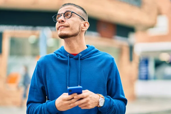 Joven Hombre Hispano Sonriendo Feliz Usando Smartphone Ciudad —  Fotos de Stock