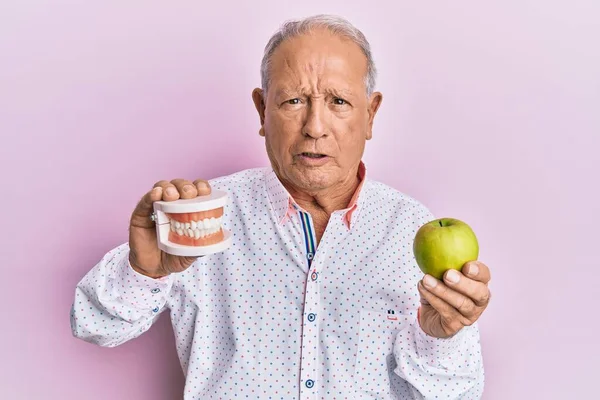 Homem Caucasiano Sênior Segurando Dentadura Maçã Verde Cético Nervoso Franzindo — Fotografia de Stock