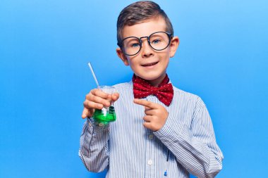 Bilim adamı papyonu takan, elinde test tüpü tutan sevimli sarışın çocuk mutlu bir şekilde elini ve parmağını gösterdi. 