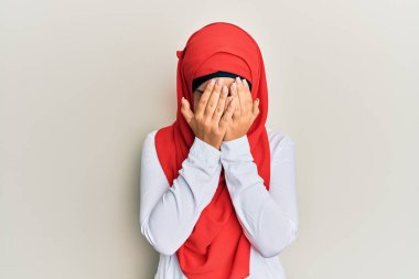 Geleneksel İslami başörtüsü takan genç, güzel İspanyol bir kız. Ağlarken yüzünü ellerle kapatan üzgün bir ifade var. depresyon kavramı. 