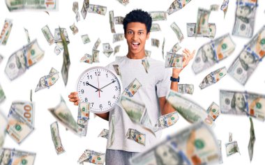 Genç Afrikalı Amerikalı adam büyük bir saat tutuyor zaferi mutlu bir gülümsemeyle ve kazanan yüz ifadesiyle kutluyor.