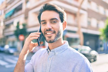 Genç İspanyol adam gülümsüyor. Şehirdeki akıllı telefondan konuşuyor..