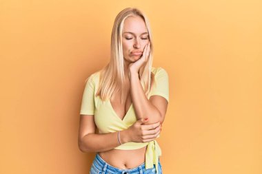 Sıradan kıyafetler giyen genç sarışın kız kollarını kavuşturarak depresyondan sıkılmış ve yorgun görünüyor.. 