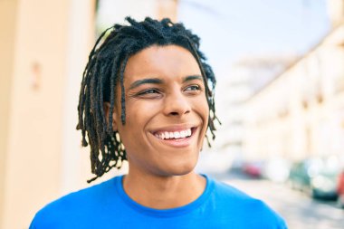 Genç Afrikalı Amerikalı gülümseyen mutlu bir adam şehrin caddesine bakıyor..