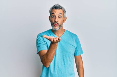 Orta yaşlı, gri saçlı, sıradan kıyafetler giyen, kameraya bakıp havada öpüşen, güzel ve seksi bir adam. aşk ifadesi. 