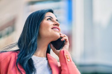 Genç ve güzel iş kadını gülümsüyor. Şehirdeki akıllı telefondan konuşuyor..