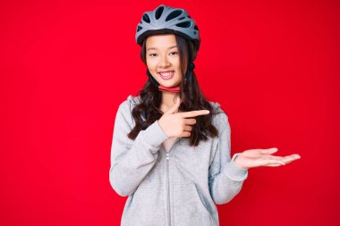 Bisiklet kaskı takan genç ve güzel Çinli kız kameraya hayret ediyor ve gülümsüyor.. 