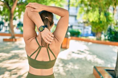 Genç sarışın sporcu kadın arka planda spor giyerek şehirde esniyor..