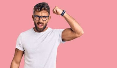 Gündelik kıyafetler giyen, gözlüklü, kızgın, kızgın, sinirli ve öfkeliyken öfkeyle bağıran genç bir İspanyol. öfke ve agresif konsept. 