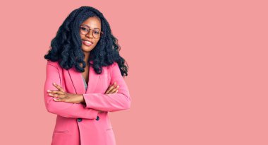 İş ceketi ve gözlük takan, kollarını kavuşturup kameraya gülümseyen güzel Afrikalı Amerikalı kadın. pozitif kişi. 