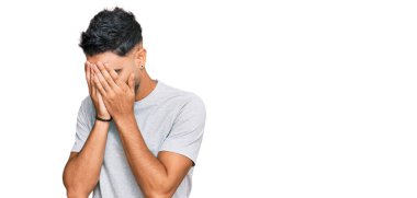 Sakallı, günlük gri tişörtlü, suratını ellerle kapatıp ağlayan genç bir adam. depresyon kavramı. 