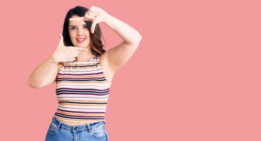 Güzel, genç, esmer, sıradan kıyafetler giyen, gülümseyen, elleri ve parmakları gülen yüzlü bir kadın. yaratıcılık ve fotoğrafçılık kavramı. 