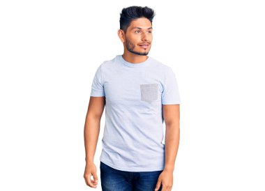 Yakışıklı Latin Amerikalı, sıradan kıyafetler giyen, yüzünde gülümsemeyle yan yana bakan, doğal bir ifade. Kendinden emin gülen. 