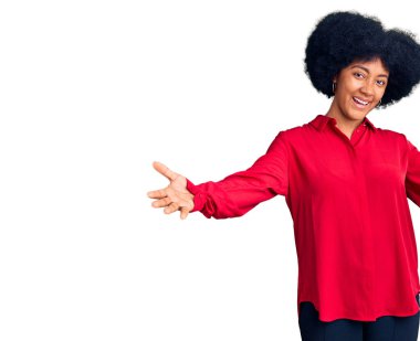 Gündelik giysiler giymiş genç Afro-Amerikan kız kameraya sarılıp gülümseyerek bakıyor. Mutluluğu kucaklayan neşeli bir ifade.. 