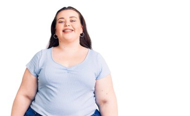 Yüzünde mutlu ve havalı bir gülümseme olan sıradan kıyafetler giyen genç ve iri yarı bir kadın. şanslı kişi. 