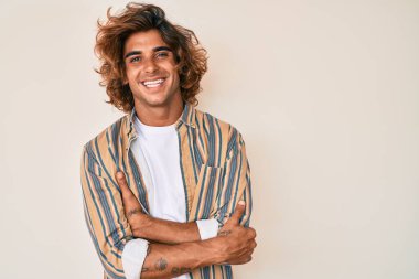 Gündelik kıyafetler giyen, kollarını kavuşturup kameraya gülümseyen genç İspanyol adam. pozitif kişi. 