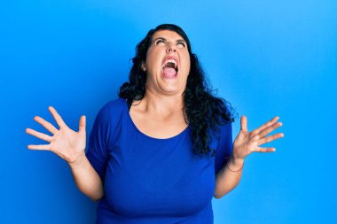 Artı mavi gömlekli esmer kadın deli deli deli bağırıyor ve agresif bir ifade ve kollarla bağırıyor. hüsran kavramı. 
