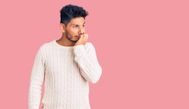 Kış süveteri giyen yakışıklı Latin Amerikalı genç adam elleri ağızda tırnak yerken gergin ve stresli görünüyor. anksiyete. 