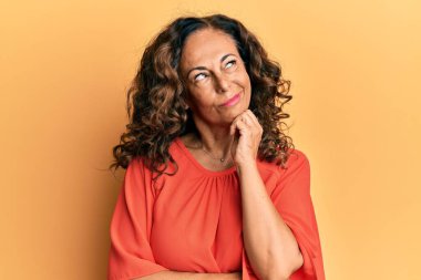 Orta yaşlı İspanyol kadın, gündelik kıyafetler giyiyor ciddi yüz ifadesi, eli çeneli soruyu düşünüyor, kafa karıştırıcı bir fikir. 