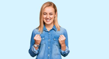 Sıradan kot ceket giyen güzel beyaz bir kadın başarı için heyecanlanıyor kolları havada ve gözleri kapalı zaferi kutluyor. Kazanan konsept. 