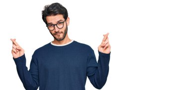 Gündelik kıyafetler giyen ve gözlüklü genç İspanyol adam umut ve gözlerin kapalı gülümseyerek el sallıyor. Şans ve batıl inançlar. 