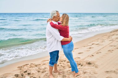 Orta yaşlı İspanyol çift sahilde öpüşüyor ve sarılıyorlar.