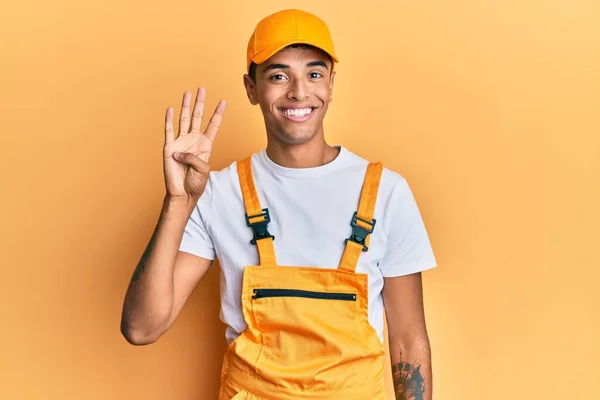 若いですハンサムなアフリカ系アメリカ人男性身に着けています手ぬるい制服上の黄色の背景表示と指差し込み指番号4ながら笑顔自信と幸せ — ストック写真