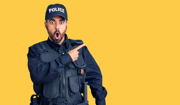 警察の制服を着た若いヒスパニック系の男が驚いた顔を指で指差して 口を開けて驚いた表情 — ストック写真