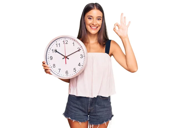 Young Hispanic Woman Holding Big Clock Doing Sign Fingers Smiling — Φωτογραφία Αρχείου