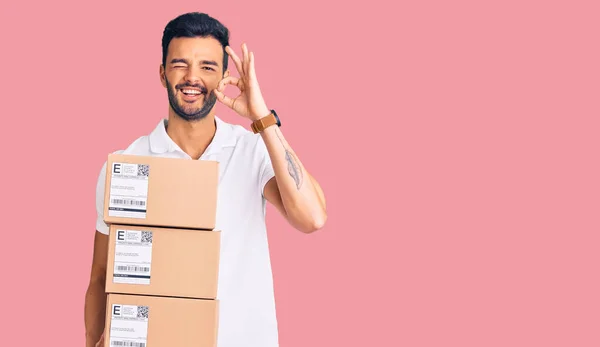 Homem Hispânico Bonito Jovem Segurando Pacote Entrega Fazendo Sinal Com — Fotografia de Stock