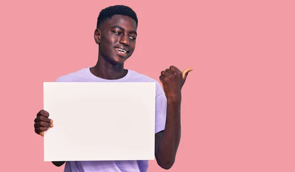 Молодий Афроамериканець Тримає Порожній Прапор Вказує Пальцем Бік Посміхаючись Задоволений — стокове фото