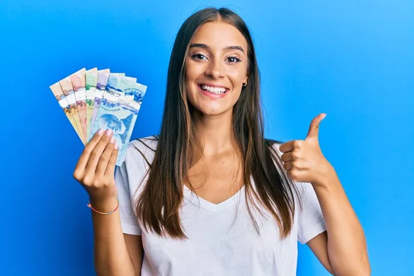Young Hispanic Woman Holding Canadian Dollars Smiling Happy Positive Thumb — Stockfoto
