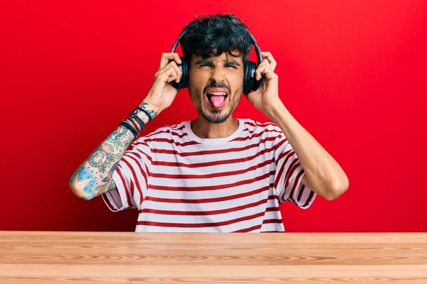 Junger Hispanischer Mann Mit Kopfhörern Sitzt Auf Dem Tisch Und — Stockfoto