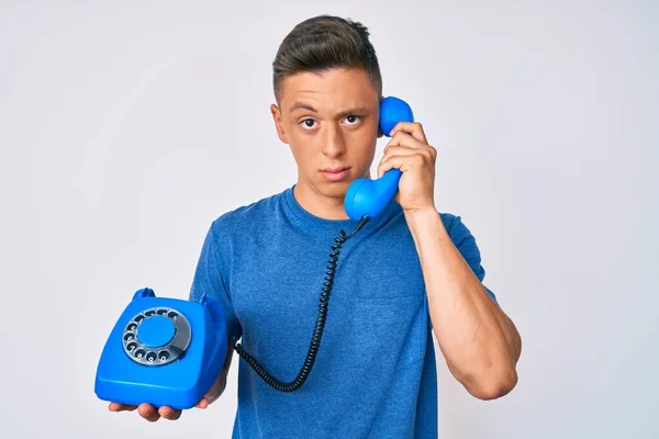 Ung Latinamerikansk Pojke Håller Vintage Telefon Skeptisk Och Nervös Rynkar — Stockfoto