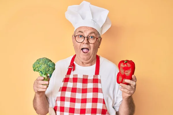 Senior Γκριζομάλλης Άνδρας Φορώντας Επαγγελματική Ποδιά Μάγειρας Κρατώντας Μπρόκολο Και — Φωτογραφία Αρχείου