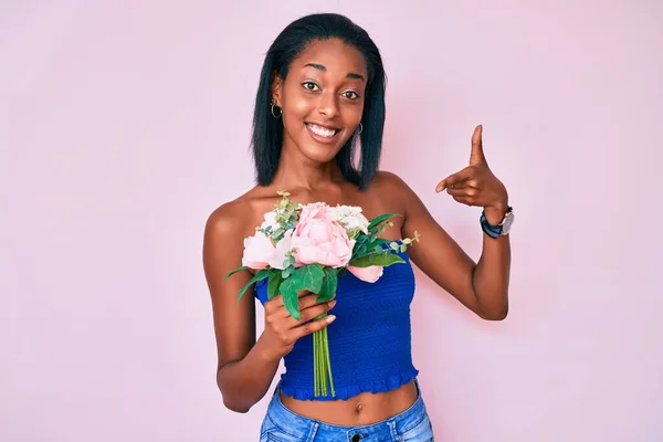 Joven Mujer Afroamericana Sosteniendo Flores Sonriendo Feliz Señalando Con Mano — Foto de Stock
