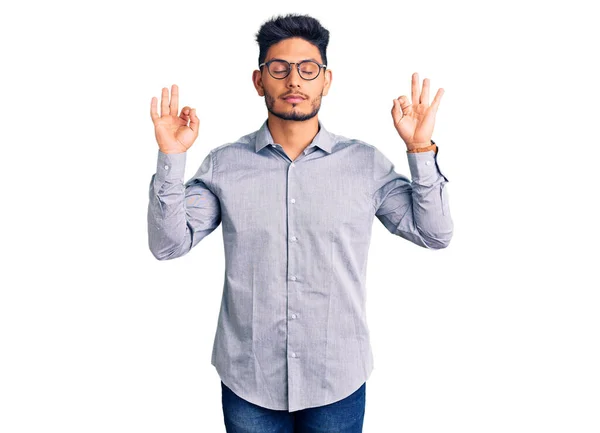 英俊的拉丁裔美国年轻人 身穿商务服装 戴着眼镜 微笑着 闭上双眼 用手指做冥想手势 瑜伽概念 — 图库照片