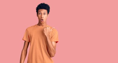 Gündelik giysiler giymiş genç Afro-Amerikan bir adam elleri yandan işaret ederek şaşırdı, ağzı açık hayret içinde kaldı.. 