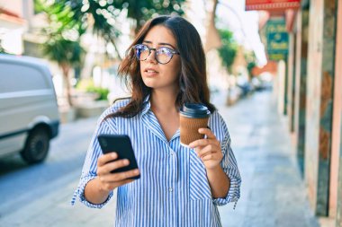 Şehirde akıllı telefon kullanan ciddi bir suratı olan genç İspanyol iş kadını..