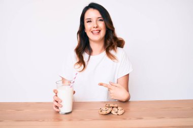 Genç, güzel esmer kadın bir bardak taze süt ve kurabiyelerle gülümsüyor. 